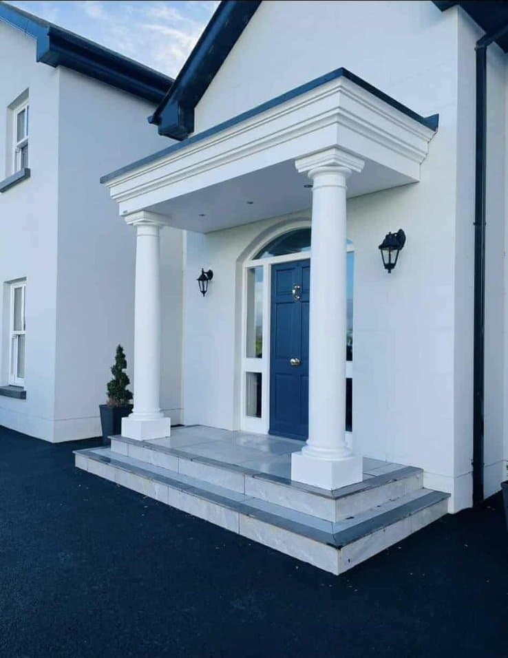 Grand portico canopy with classical white columns and blue door on detached home