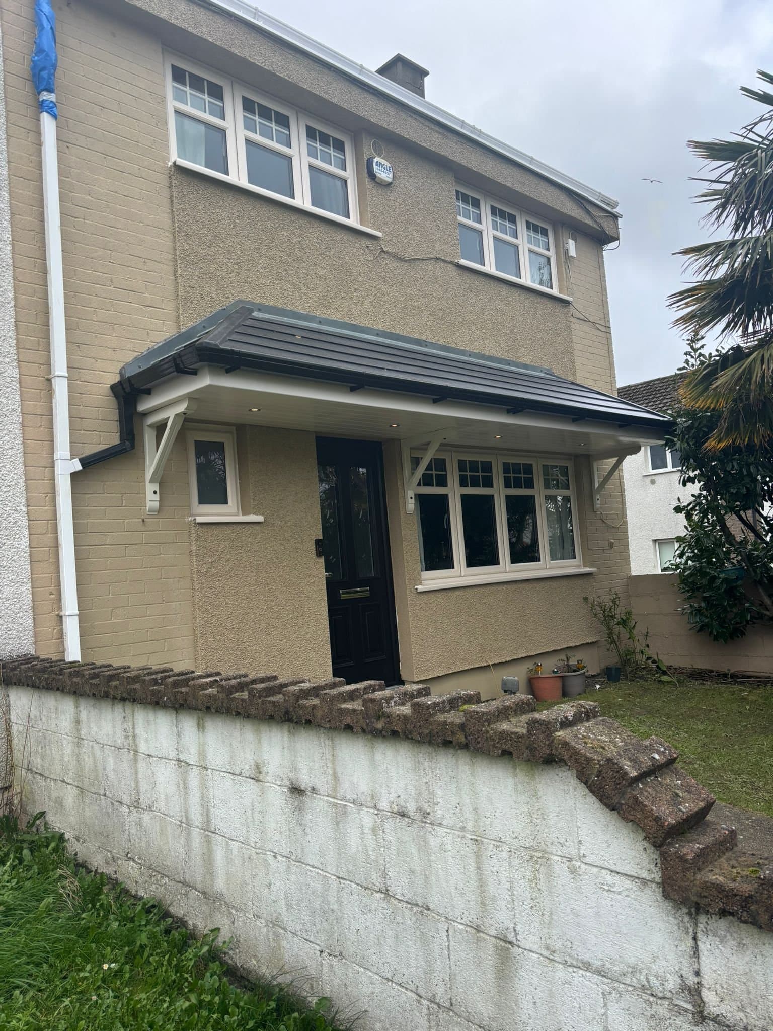 Full coverage double hip canopy spanning door and window on detached house