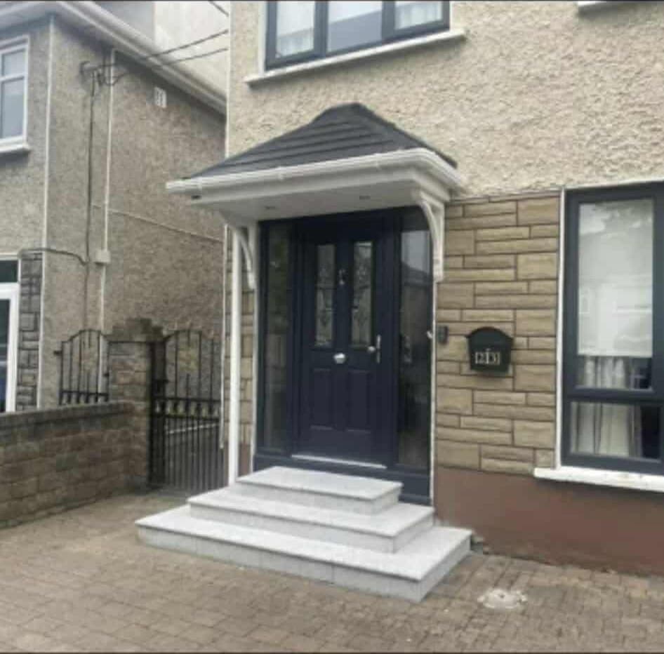 Hipped canopy with white columns over blue door and stone steps