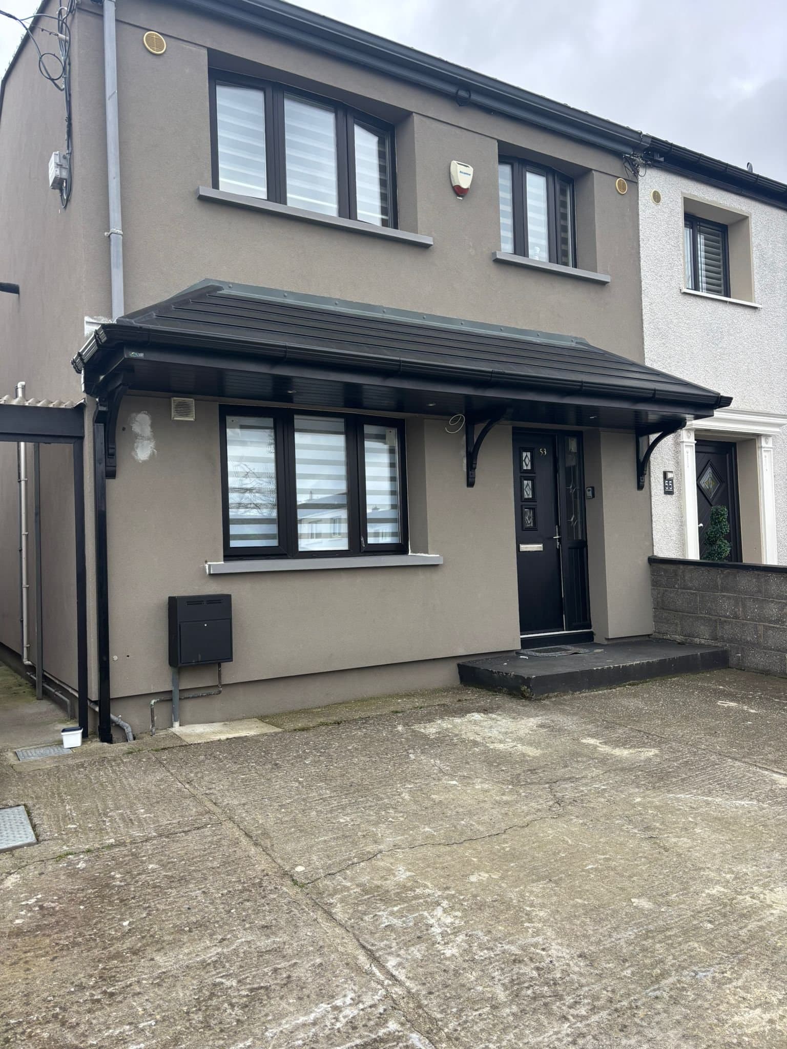 Wide double hipped canopy covering entrance and window on semi-detached home